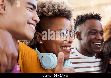 Groupe de personnes, souriant et heureux d'être ensemble. Une fille de Latina embrassant avec ses amis, un garçon afro-américain et un garçon asiatique. Concept de Banque D'Images