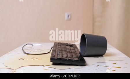 Gros plan d'un clavier imprégné de café avec une tasse retournée à proximité Banque D'Images