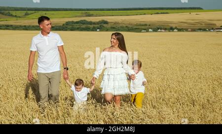 La famille avec de petits enfants marche dans le champ de blé en été Banque D'Images