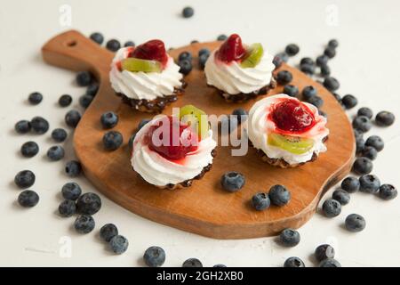 petits gâteaux avec fromage cottage sur plateau millésime-délicieux muffin avec fraise et kiwi sur assiette en bois Banque D'Images