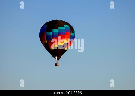 Un ballon d'air chaud coloré qui fait tourner une flamme flotte dans le ciel dans le nord de l'Idaho. Banque D'Images