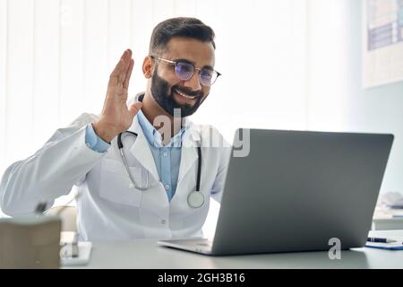 Un médecin indien agité la main en ayant une consultation virtuelle en ligne sur ordinateur portable. Banque D'Images