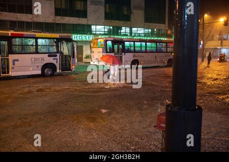 L'homme essaie de traverser une rue inondée avec de l'eau à genoux dans le quartier de Copacabana. Banque D'Images