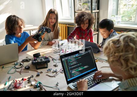 Divers élèves des écoles construisent des voitures robotisées à l'aide d'ordinateurs et de codage. Banque D'Images