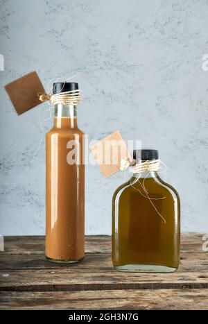 deux bouteilles de liqueurs artisanales sur table rustique en bois. fond gris. horizontal Banque D'Images