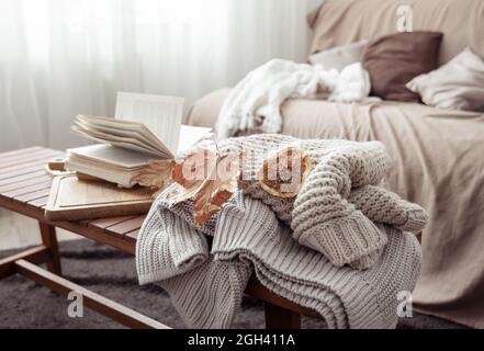 Une composition chaleureuse avec un pull tricoté, un livre et des feuilles à l'intérieur de la pièce. Banque D'Images
