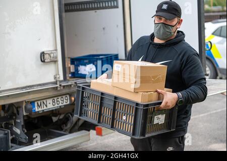 Riga, Lettonie - 3 septembre 2021 : un homme avec un masque décharge les boîtes d'un camion, livraison de marchandises Banque D'Images