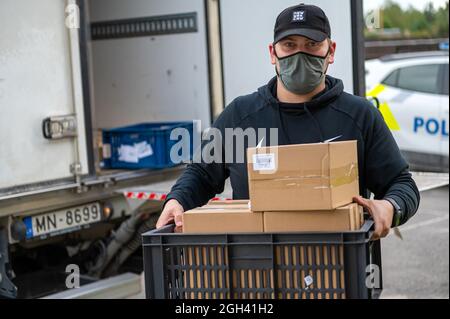 Riga, Lettonie - 3 septembre 2021 : un homme avec un masque décharge les boîtes d'un camion, livraison de marchandises Banque D'Images
