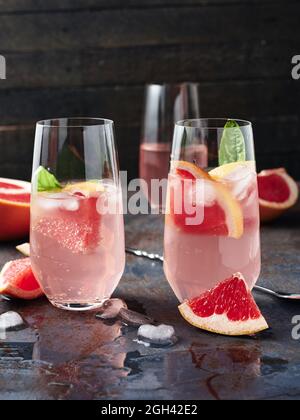Deux verres de boisson froide avec des feuilles de pamplemousse et de basilic. Banque D'Images
