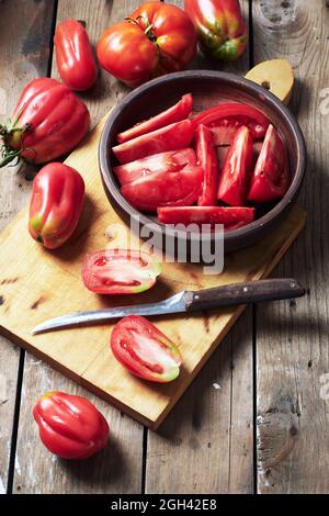 Tomates fraîches pour faire de la sauce tomate sur une planche à découper en bois. Banque D'Images