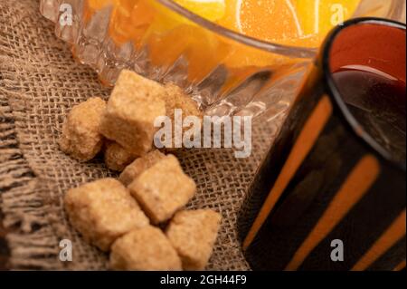 Tranches de citron marmelade multicolores dans un vase en verre, morceaux de sucre de canne brun et une tasse de café, gros plan, mise au point sélective Banque D'Images