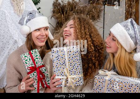 jeunes filles ayant plaisir emballer des cadeaux à la maison, grand travail d'équipe d'amis emballer des cadeaux pour noël, se préparer pour le prochain an et noël Banque D'Images