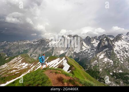 Vue aérienne d'Un randonneur se tenant au sommet de l'incroyable sommet de Maja e Vajushës (pic de talijanka) dans la chaîne de montagnes de Prokletije regardant les pics de Karanfili Banque D'Images