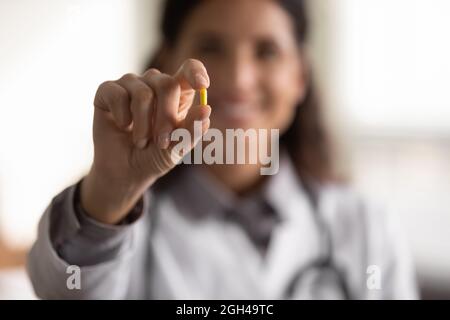 Bonne femme médecin montrant le médicament, tenant la pilule jaune à l'appareil photo Banque D'Images