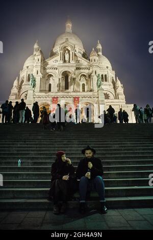 Couple buvant du vin en face de la basilique du Sacré Cœur de Montmartre par nuit, Paris Banque D'Images