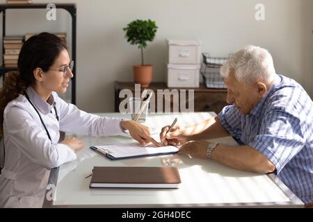 Homme senior remplissant le document juridique d'assurance à un rendez-vous avec un médecin Banque D'Images