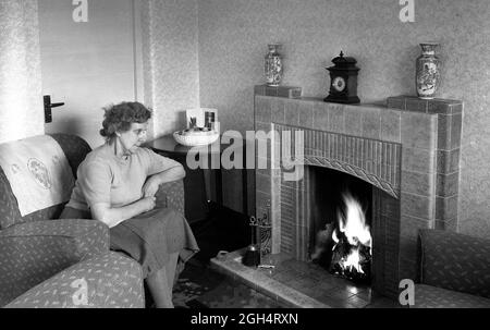 Maison douce maison âgée femme assise près de son feu de charbon dans une maison de conseil Grande-Bretagne 1952 Banque D'Images