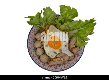 Faire bouillir les nouilles aux œufs avec le ballon de porc, le porc haché, l'œuf frit et les légumes isolés sur fond blanc avec un passe-cheveux. Mise au point sélective. Banque D'Images