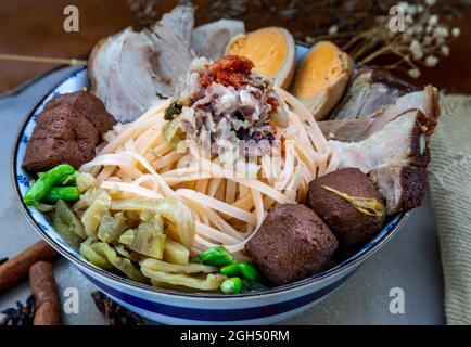 Nouilles de porc chinoises traditionnelles en tranches avec bouillon d'os de porc et œuf dur, tofu dans un bol en céramique. Cuisine asiatique, concentration sélective. Banque D'Images