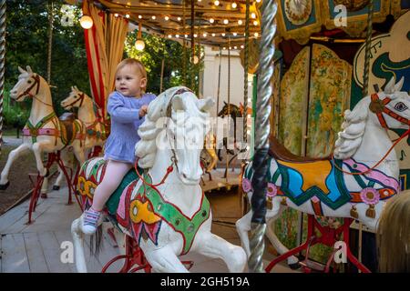 Petite fille mignonne sur le cheval du vieux carrousel rétro, Prague, république Tchèque Banque D'Images