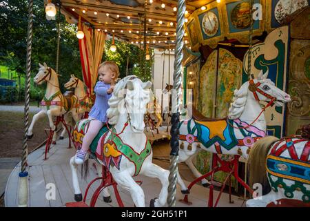 Petite fille mignonne sur le cheval du vieux carrousel rétro, Prague, république Tchèque Banque D'Images