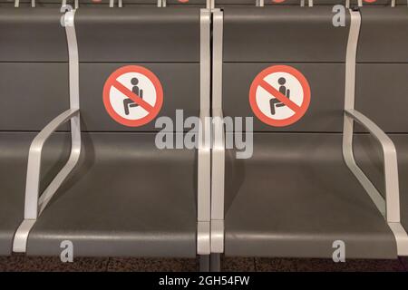 BARCELONE, ESPAGNE - 18,2021 AOÛT : deux sièges dans le terminal de départ de l'aéroport de Barcelone sans siège et avec les panneaux de distance Banque D'Images