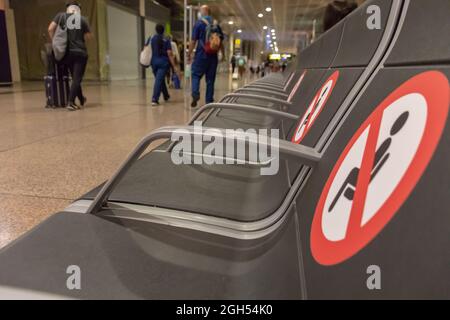 BARCELONE, ESPAGNE - AOÛT 18,2021 : rangée de sièges dans le terminal de départ de l'aéroport de Barcelone sans siège et avec les panneaux de distance Banque D'Images