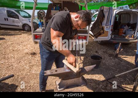 Un forgeron, un farrier, un clawing et la mise en forme d'un fer à cheval sur un Anvil, avec un pinceau, Espagne. Banque D'Images