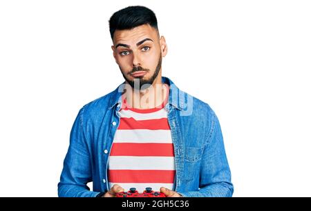 Jeune homme hispanique avec la barbe jouant jeu vidéo tenant contrôleur enfoncé et s'inquiéter de la détresse, pleurant en colère et peur. Expression triste. Banque D'Images