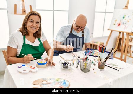 Le peintre hispanique d'âge moyen couple souriant Happy Painting au studio d'art. Banque D'Images