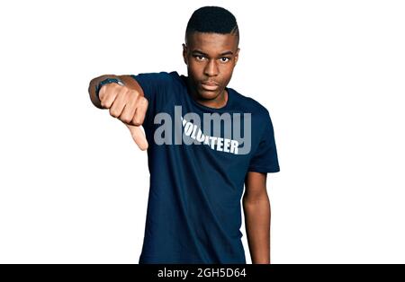 Jeune afro-américain portant le t-shirt de volontaire a l'air malheureux et en colère montrant le rejet et négatif avec le pouce vers le bas geste. Mauvaise expression Banque D'Images