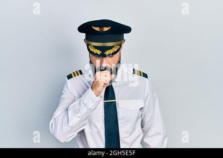 Jeune homme hispanique portant un uniforme de pilote d'avion se sentant mal et toussant comme symptôme de rhume ou de bronchite. Concept de soins de santé. Banque D'Images