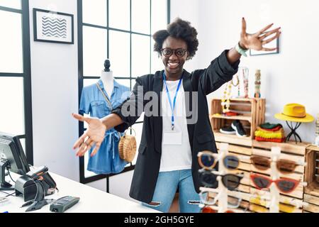 Une jeune femme africaine qui travaille en tant que directrice de la boutique en ligne, regarde la caméra en souriant aux bras ouverts pour se faire hucher. Une expression gaie embrassant les happines Banque D'Images