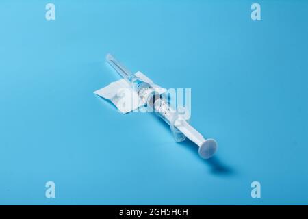 Le vaccin est dactylographié dans une seringue avec le vaccin sur fond bleu Banque D'Images