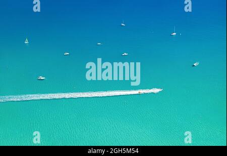 Hors-bord et curseur à vagues laissant le sentier sur l'eau, avec d'autres bateaux et la mer comme arrière-plan avec l'espace de copie. Paysage marin aérien Banque D'Images