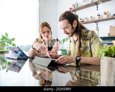 Des créateurs masculins et féminins dessinant des esquisses sur des tablettes graphiques tout en travaillant ensemble sur un projet dans l'espace de travail Banque D'Images