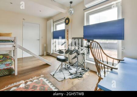 Tambour électronique placé près de la fenêtre dans une chambre moderne avec lits superposés et table avec chaise dans un appartement de style loft Banque D'Images