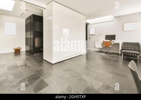 Décoration minimaliste de style loft dans un hall moderne spacieux avec murs blancs et sol en marbre, fauteuils et maquette blanche Banque D'Images