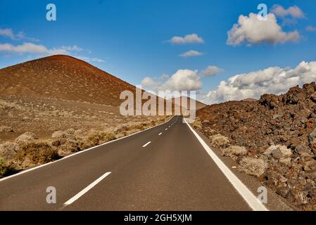 Route asphaltée droite traversant le champ vers la montagne le matin à Fuerteventura, Espagne Banque D'Images