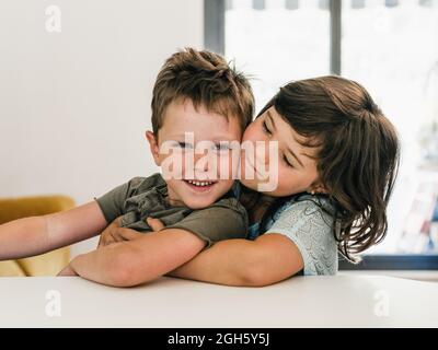 Des jumeaux adorables se embrassent tendinement et s'assoyent ensemble dans le salon à la maison