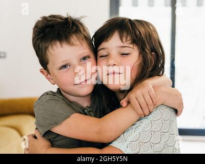 Des jumeaux adorables se embrassent tendinement et s'assoyent ensemble dans le salon à la maison