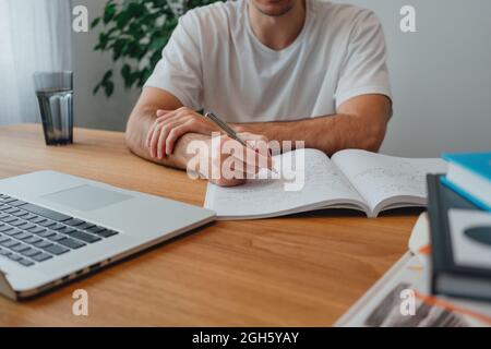 Étudiant au campus tout en étudiant l'apprentissage en ligne pour passer l'examen à l'université. Un homme pensif étudie avec un ordinateur portable à la maison Banque D'Images