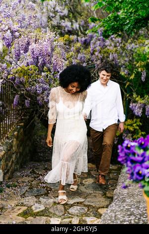 Surfeur mâle en combinaison avec aviron à paddle-board en mer eau sur fond de montagnes au coucher du soleil Banque D'Images