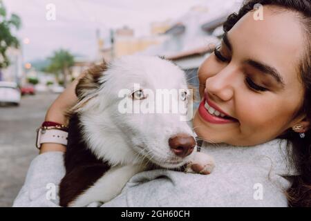 Une femme ravie embrasse un adorable chien Border Collie et souriait avec les yeux fermés Banque D'Images