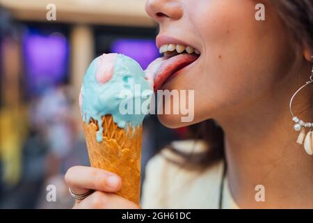 Croquer de jeunes femelles savoureuses gelato dans le cône de gaufré en ville sur fond flou Banque D'Images