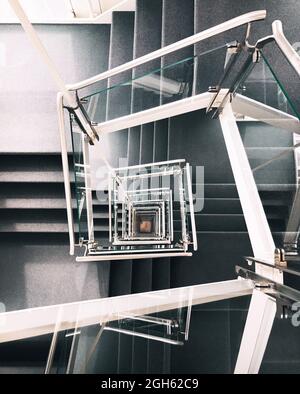 Depuis le dessus de l'escalier en colimaçon créatif avec des marches en béton et une rampe en verre dans le bâtiment contemporain de Hambourg Banque D'Images
