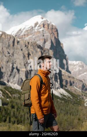 Vue latérale de l'homme en voyage avec sac à dos en haut de la colline pendant le trekking dans les Dolomites Mountains Banque D'Images