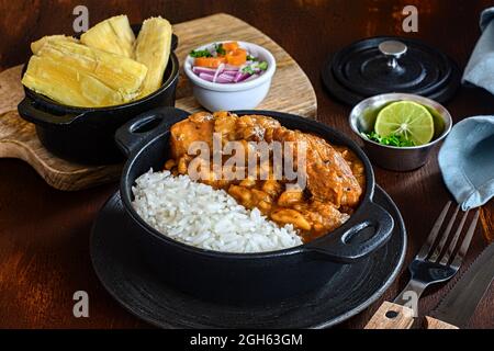 Délicieux plat de riz avec ragoût de pommes de terre déshydratées et tranches de viande contre le manioc cuit et la salade de légumes sur la planche à découper Banque D'Images