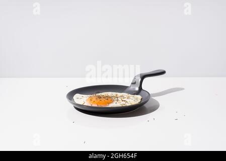 Délicieux œuf frit sur une poêle noire servi sur une table sur fond blanc en studio Banque D'Images