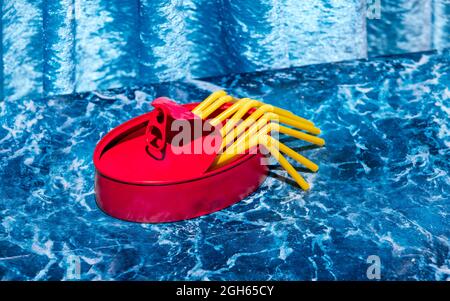 Boîte en aluminium rouge avec pailles jaunes montrant le concept de conserves de fruits de mer sur table en marbre bleu dans le studio Banque D'Images